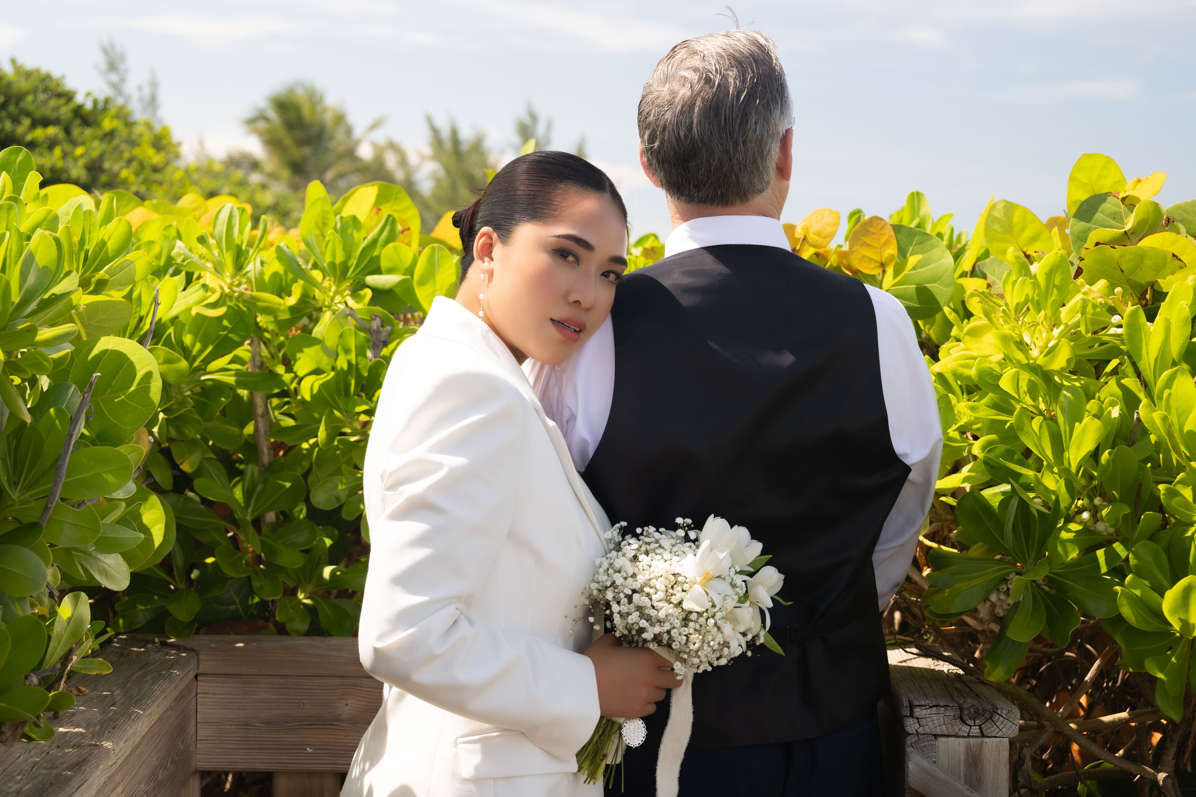 Bride looking back over shoulder holding bouquet on boardwalk
