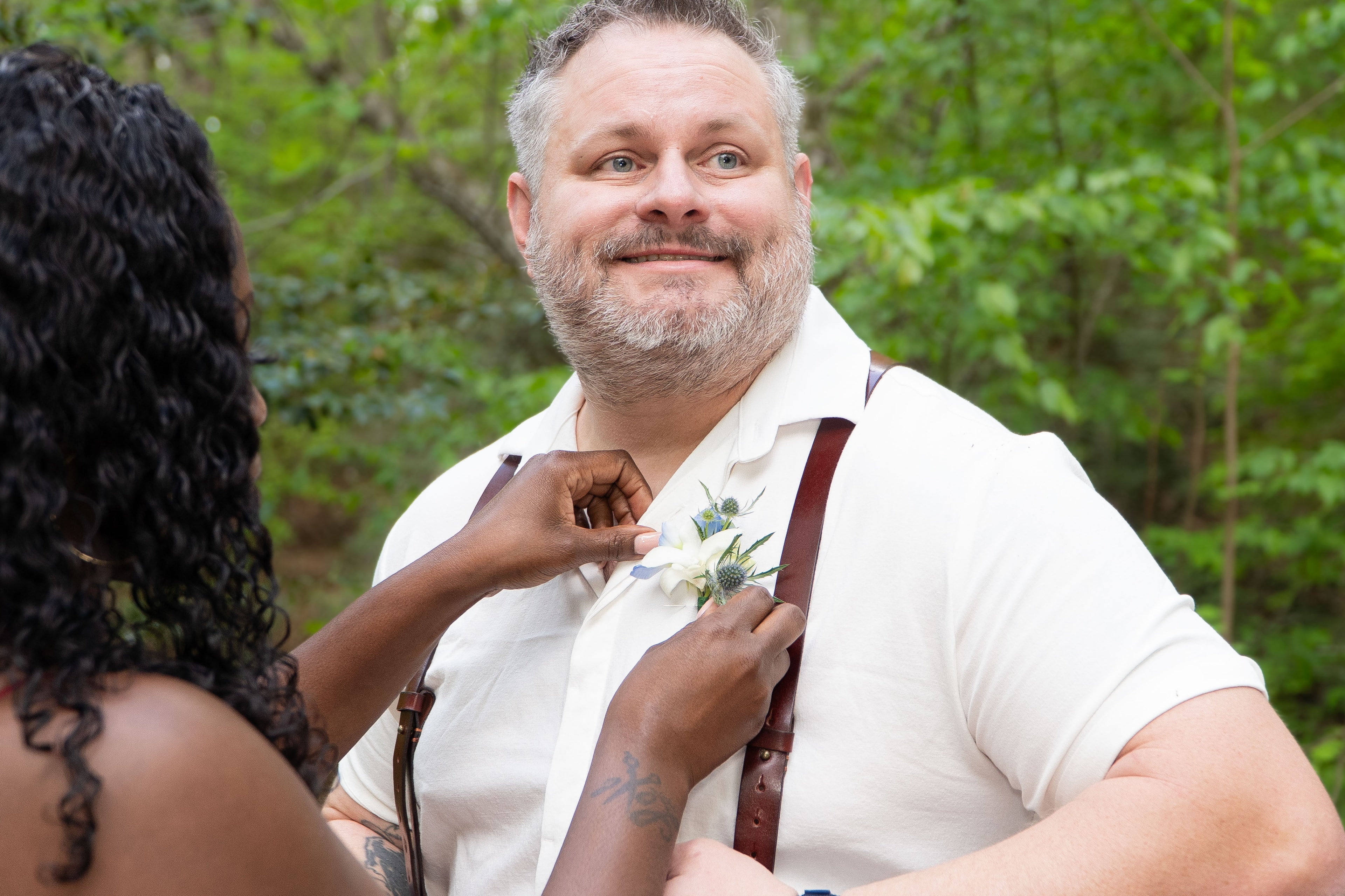 Bride pinning boutonniere on groom