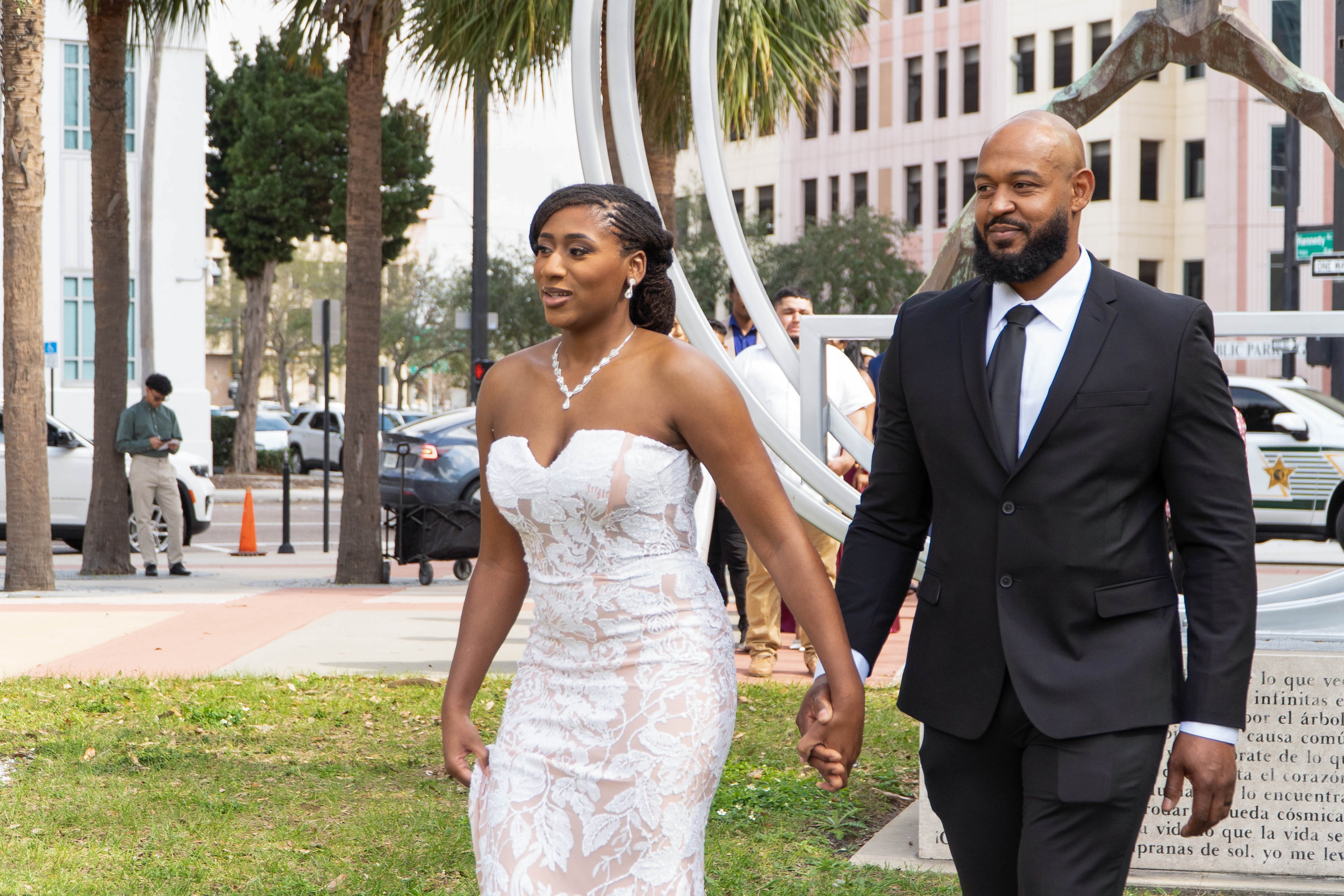 Bride and groom walking hand in hand past palm trees